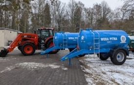 Traktor i cysterny na gminnym placu, zimowa sceneria