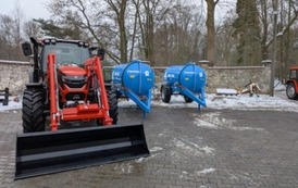 Traktor i dwie cysterny stoją na placu gospodarczym