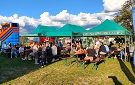 Piknik, zdjęcie namiot&oacute;w i siedzący na ławkach ludzie